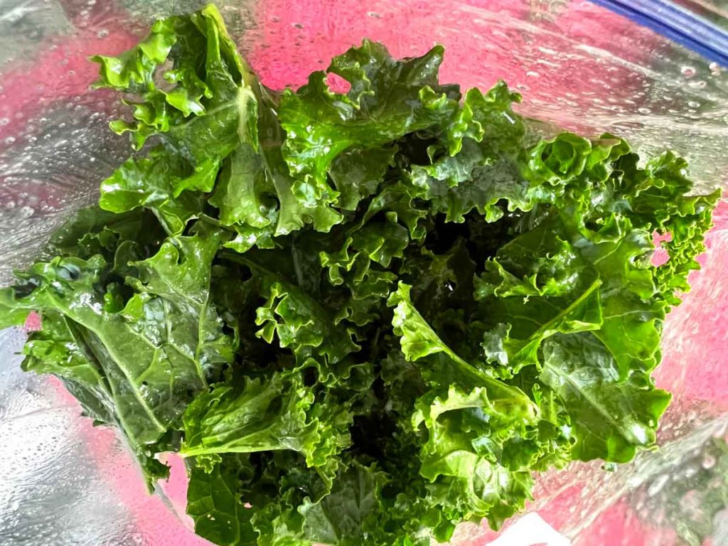 raw kale in bag with oil spray
